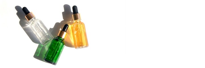 banner three glass bottles with pipettes with beautiful sun shadows, cosmetics of different types...