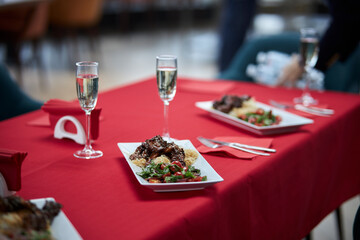 served table, sweet and sour chicken with sesame seeds on a white plate and glasses of champagne
