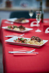 served table, sweet and sour chicken with sesame seeds on a white plate and glasses of champagne