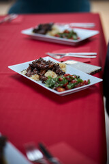 served table, sweet and sour chicken with sesame seeds on a white plate and glasses of champagne