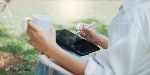 Cropped photo, young asian woman in casual clothes using digital tablet working online outdoor, female investor use tablet computer to trading stock and shopping or paying online