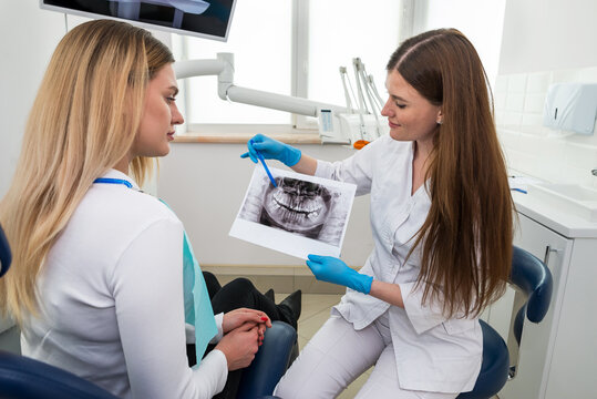 Professional dentistry. A female dentist who knows her business shows a picture to a patient with bad teeth.