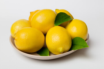Fresh cutted lemon and whole lemons over round plate on colored background. Food and drink ingredients preparing. healthy eating theme top view vith copy space