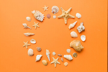 Summer time concept on colored background. Seashells from ocean shore in the shape of frame separated with space for text top view