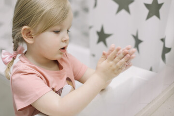 Naklejka premium Little toddler girl in bathroom washing hands. Healthy, Child Hygiene concept.