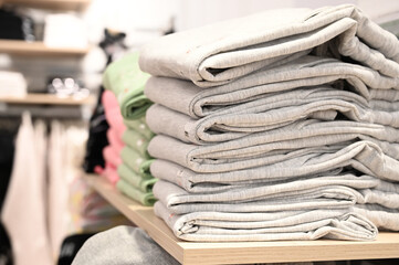 Side view of stack of clothes lies on the store shelf. Clothes sale.
