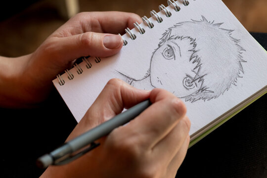 girl draws a human face in anime style with a pencil