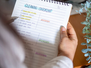 Woman planning a spring cleaning checklist routine for the household. Handwriting To-do list for...