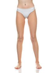 Front view of female barefoot legs in white bikini panties on a white studio background