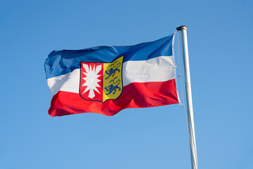 Flag of Schleswig-Holstein in front of blue sky