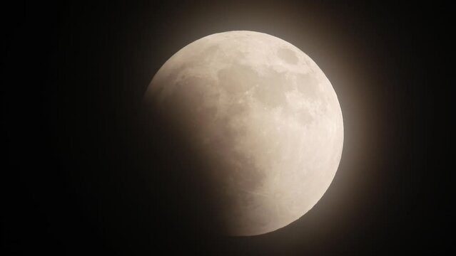 Time Lapse of lunar eclipse glowing Moon light up in night dark slowly moving on Black sky