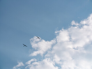Glider near clouds. Small plane pulls glider to the sky to start the gliding flight. Thy sky is blue with some clouds. 