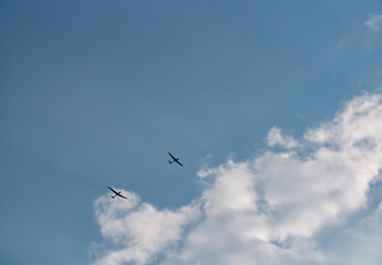 Small plane pulls glider to the sky to start the gliding flight. Thy sky is blue with some clouds.