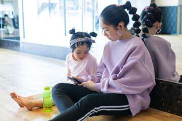 スマートフォンを見ている小学生と幼児の女の子