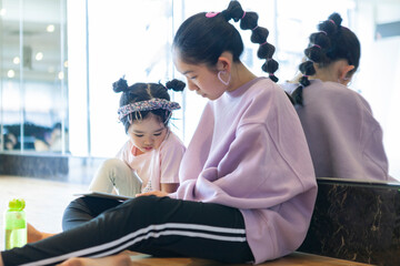 デジタルタブレットで遊んでいる小学生と幼児の女の子