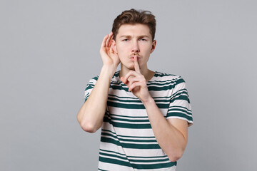 Young curious nosy man 20s in blue striped t-shirt try to hear you overhear listening intently says...
