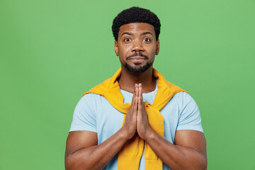 Young man of African American ethnicity 20s wear blue t-shirt hold hands folded in prayer gesture,...