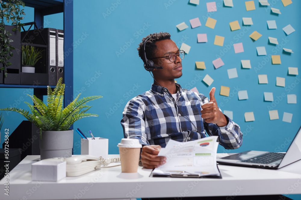 Poster helpline center operator wearing headset, showing thumbs up approval sign while on call with custome