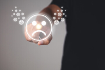 Evaluation and satisfaction concept. Index Finger of hand points to frown emotion. Close up shot on grey background.