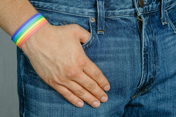 Male hand with rainbow bracelet wearing jeans. Freedom and LGBT concept