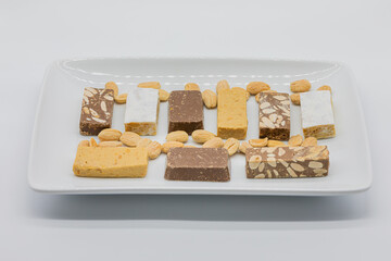 Assortment of kinds of nougat and almonds in ceramic tray isolated on a white background