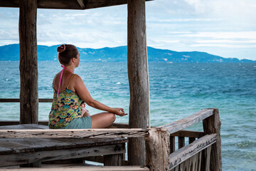 Mujer joven meditando frente a la playa. Meditación y espiritualidad