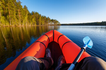A man in a packraft with a paddle on a beautiful forest lake.