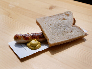 Grilled sausage on a paper plate with mustard