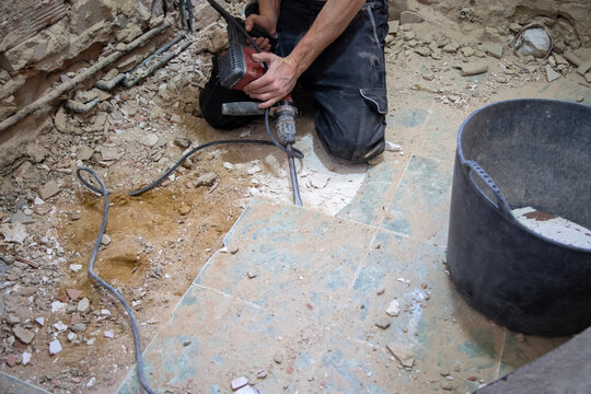 Hombre trabajando en la obra del ba&ntilde;o quitando el suelo con una maquina