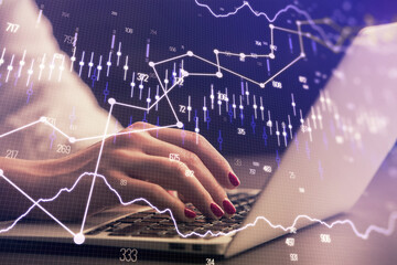 Double exposure of businesswoman hands typing on computer and forex chart hologram drawing....