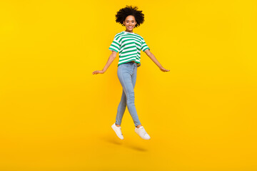 Full body photo of cute millennial lady jump wear t-shirt jeans shoes isolated on yellow background