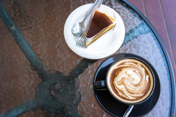 Hot coffee latte with latte art milk foam in cup mug and Homemade chocolate cake on wood desk on top view. As breakfast In a coffee shop at the cafe,during business work concept