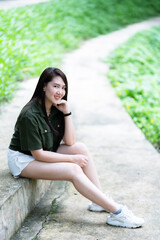 a portrait of beautiful happy asian woman traveler wearing brownish green dress stylish hipster Summer sunny lifestyle on the street outdoors at sunny summer day in park background