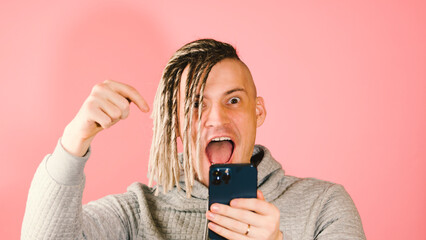 Man with dreadlocks uses a smartphone and is very and sincerely happy about the online victory. A...