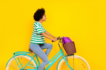 Profile photo of nice young lady ride bicycle wear t-shirt jeans bag isolated on yellow background - obrazy, fototapety, plakaty