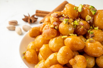 luqaimat or lokma close-up. Traditional Arabic sweet sprinkled with nuts. White table.