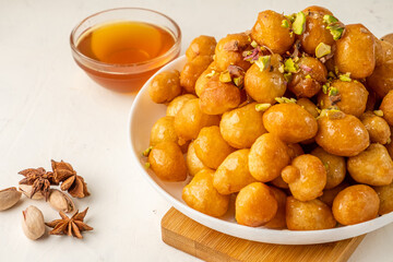 luqaimat balls of fried dough in sweet honey syrup on a light background close-up. Traditional dessert.