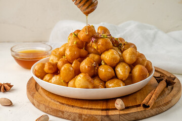 luqaimat is a traditional sweet, fried dough in honey syrup. Honey flows from a honey spoon to lokma