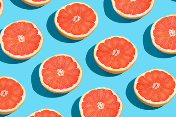 Many fresh slices of grapefruits on blue background, flat lay. Pattern design