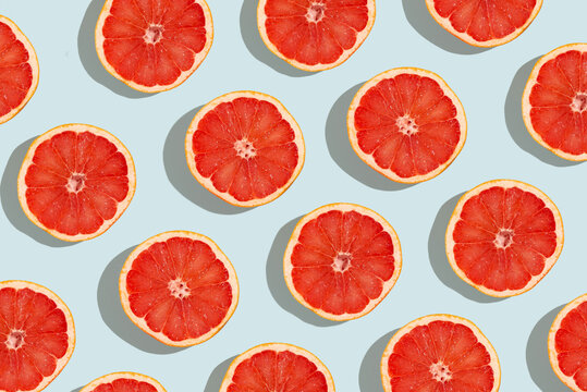 Many fresh slices of grapefruits on turquoise background, flat lay. Pattern design