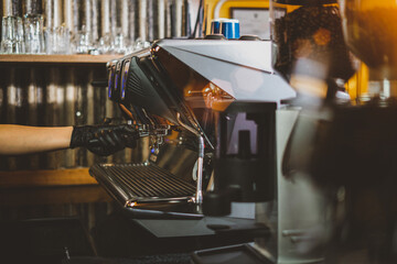 Close-up image of a coffee machine in a Cafe coffee shop or restaurant. Barista making hot coffee from a professional modern espresso brewing machine by a bottomless filter. Cafe Service Concept