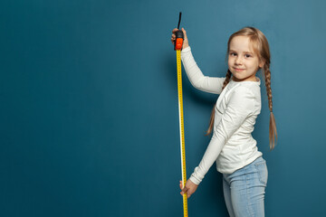 Cute child is playing. Kid measures on blue background portrait. Concept of education.