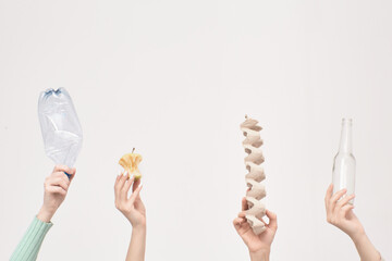 Banner, hands hold plastic, apple, paper, cardboard, glass against the background of the white wall, the concept of environmental protection. Save clean planet.
