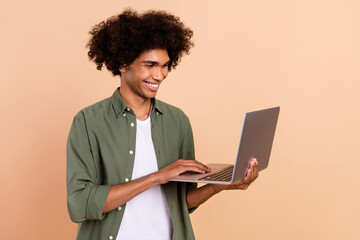 Portrait of attractive cheerful skilled wavy-haired guy using laptop typing email isolated over...