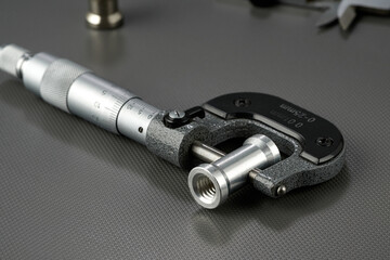 Closeup of a mechanical micrometer with a steel sleeve.