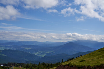 Small cozy village in mountains, with rural area at highland in autumn. Aerial view of mountain settlement, with small houses and amazing rolling hills landscape on background. Concept of highland.