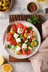 Greek salad. Fresh Greek salad with fresh vegetables, tomato, cucumber, green olives and feta cheese on old grey concrete table background. Top view.