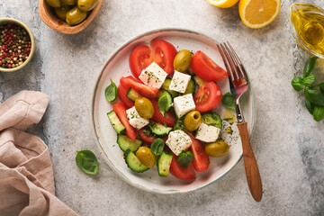 Greek salad. Fresh Greek salad with fresh vegetables, tomato, cucumber, green olives and feta cheese on old grey concrete table background. Top view.