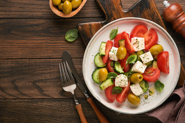 Greek salad. Fresh Greek salad with fresh vegetables, tomato, cucumber, green olives and feta cheese on old dark wooden table background. Top view.