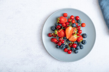 Strawberries, cherries and blueberries on a dark plate, top view